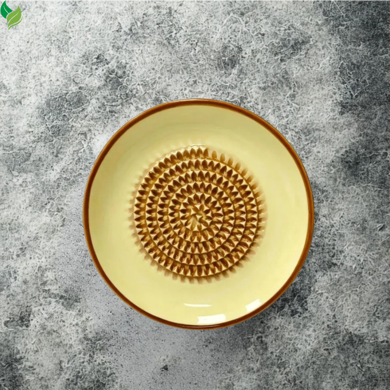 Ceramic grater dish beside fresh ginger and garlic ingredients