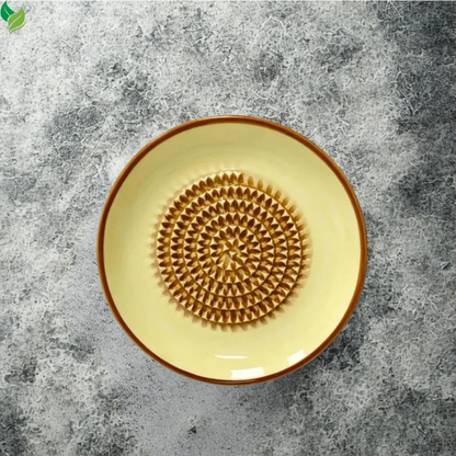 Ceramic grater dish beside fresh ginger and garlic ingredients