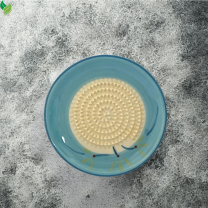 Fresh ginger pulp collected inside a round ceramic grater dish