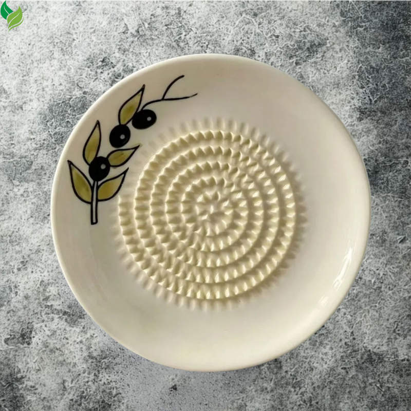 Hand rubbing peeled ginger across a ceramic grating surface