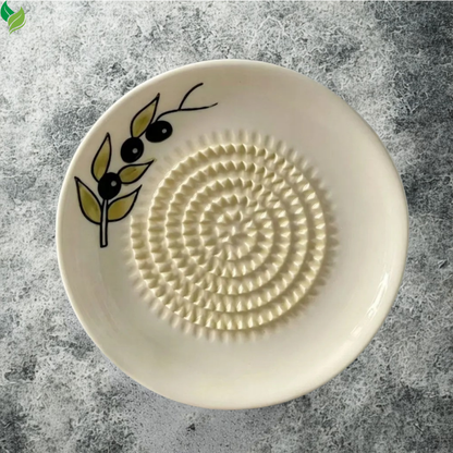 Hand rubbing peeled ginger across a ceramic grating surface