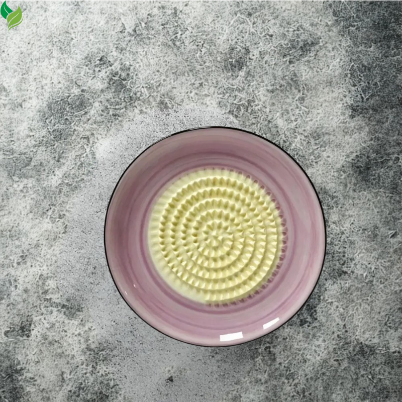 Manual ceramic grater used for preparing garlic on a kitchen counter