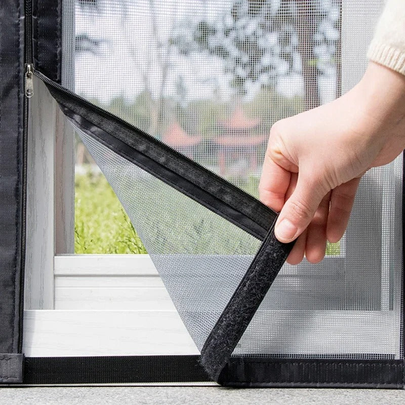 Hand pulling back the corner of a black mesh window screen to show the frame attachment.
